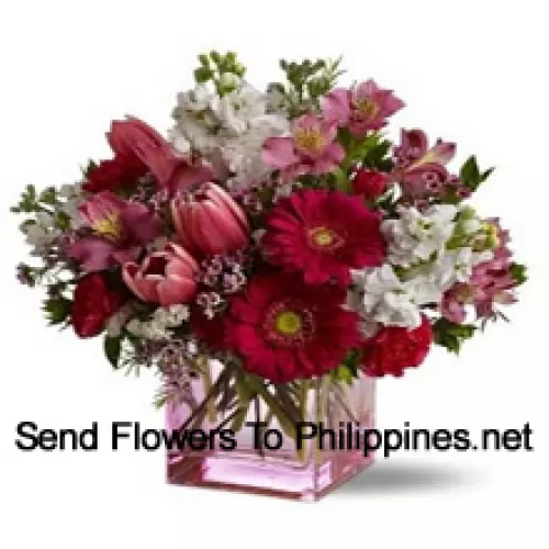 Rode rozen, rode tulpen en verschillende bloemen met seizoensvullers prachtig gerangschikt in een glazen vaas