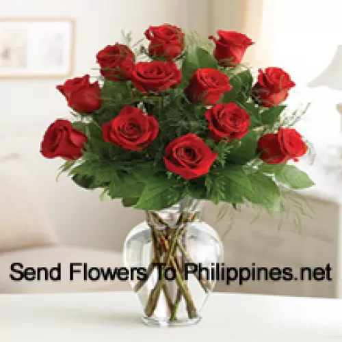 12 красных роз с папоротниками в стеклянной вазе