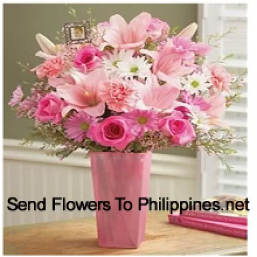 ガラスの花瓶に季節の花材と一緒にピンクのバラ、ピンクのカーネーション、ピンクのガーベラ、白いガーベラ、そしてピンクのユリが入っています